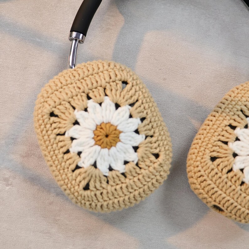 Puede incluir: Un par de fundas para auriculares de ganchillo beige con un dise&ntilde;o de margarita blanca. Las fundas est&aacute;n hechas con un punto de granny square.