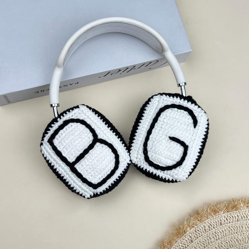 Peut inclure: Casque audio blanc et argent&eacute; avec des coussinets d'oreille en crochet. Les coussinets sont blancs avec des contours noirs et les lettres "BG" au centre. L'arceau est blanc avec un d&eacute;tail en m&eacute;tal argent&eacute;.