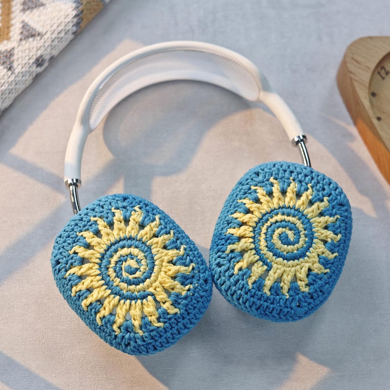 May include: White headphones with blue and yellow crocheted earmuffs featuring a sunflower design.
