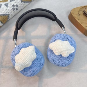 May include: Blue crocheted headphone covers with white crocheted cloud designs.