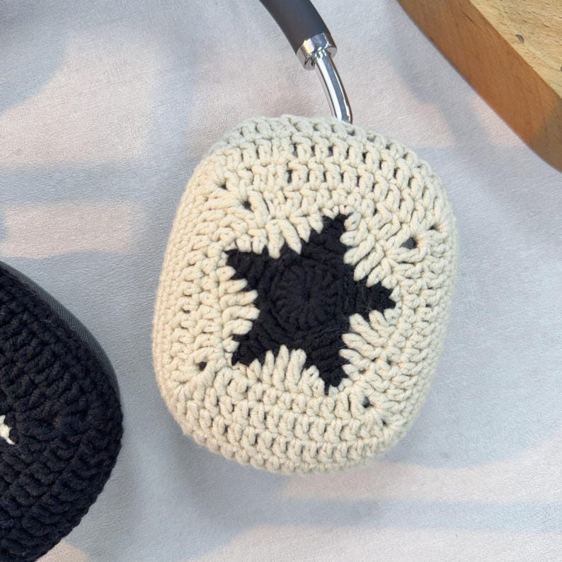 Peut inclure: Une paire de housses pour &eacute;couteurs en crochet avec un motif d'&eacute;toile noire. Les housses sont beiges et ont un motif textur&eacute; en crochet.