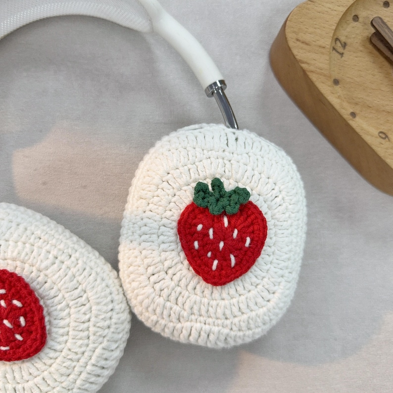 May include: White crocheted headphone covers with a red and green strawberry design.