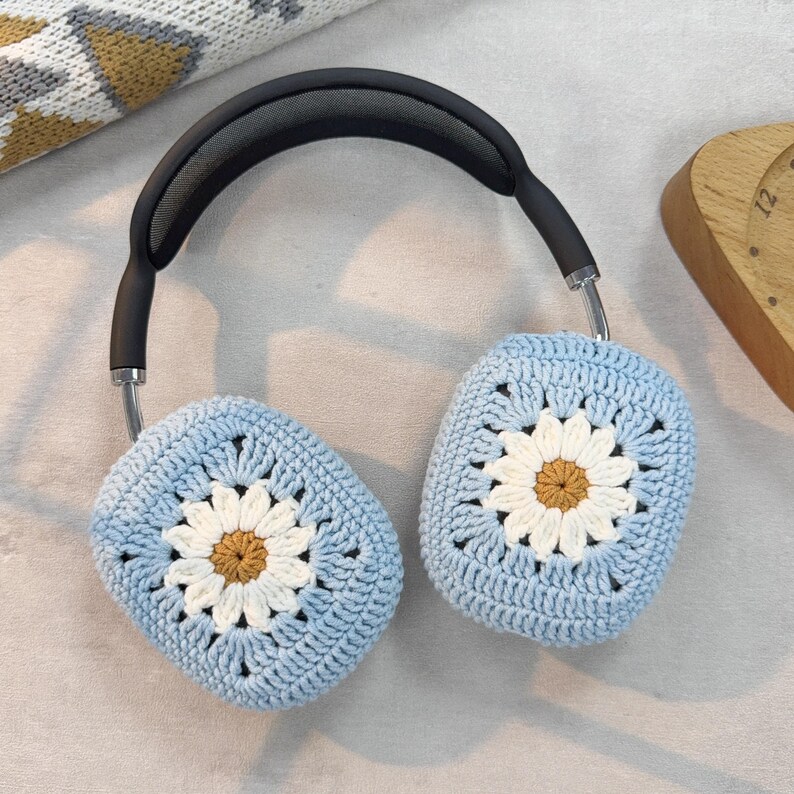 Puede incluir: Fundas para auriculares de ganchillo azul con dise&ntilde;os de margaritas blancas. Las fundas est&aacute;n hechas con un patr&oacute;n de punto de granny square.