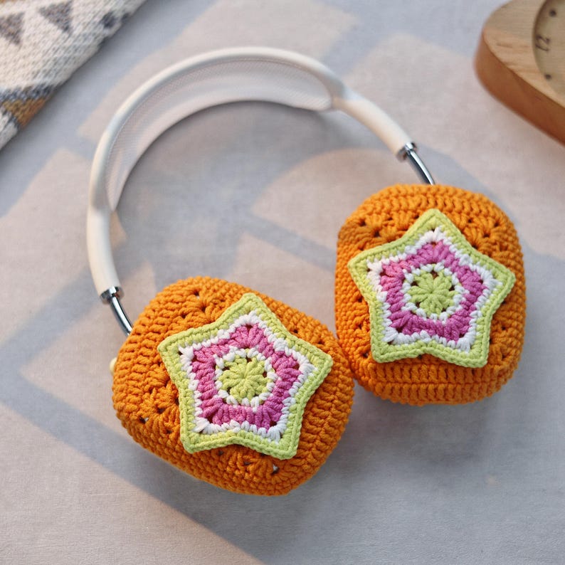 May include: Orange crocheted ear warmers with a white headband and a star-shaped design in pink, green, and white.