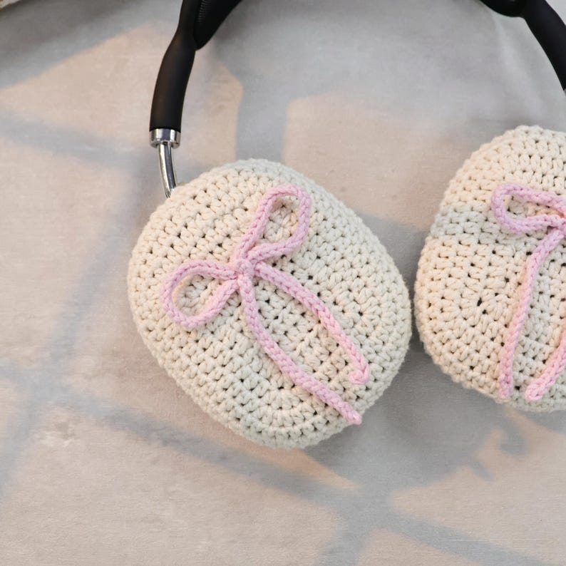 Pu&ograve; includere: Un paio di copri cuffie all'uncinetto con fiocchi rosa. Le coperture sono beige e hanno una delicata trama all'uncinetto.