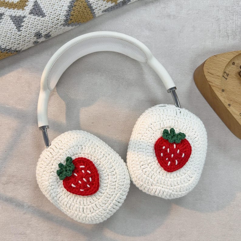 May include: White crocheted headphone covers with a red strawberry design.