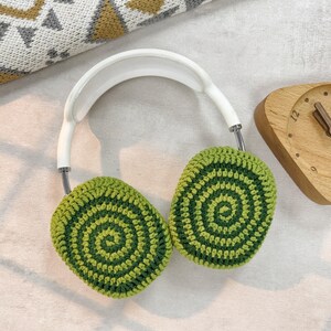 Puede incluir: Orejeras de ganchillo verde y blanco con una diadema blanca. Las orejeras tienen un patr&oacute;n en espiral.