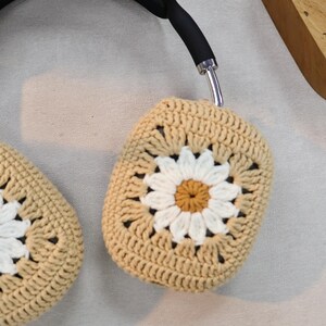 Puede incluir: Un par de fundas para auriculares de ganchillo beige con un dise&ntilde;o de margarita blanca. Las fundas est&aacute;n hechas con un patr&oacute;n de punto cuadrado.
