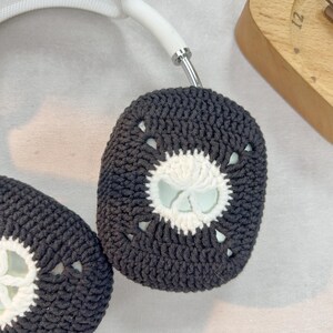 May include: Black and white crocheted earmuffs with a floral design. The earmuffs are made of soft yarn and have a comfortable fit.