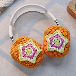May include: Orange crocheted headphone covers with a white headband. Each cover features a multi-colored star with pink, green, and white yarn.