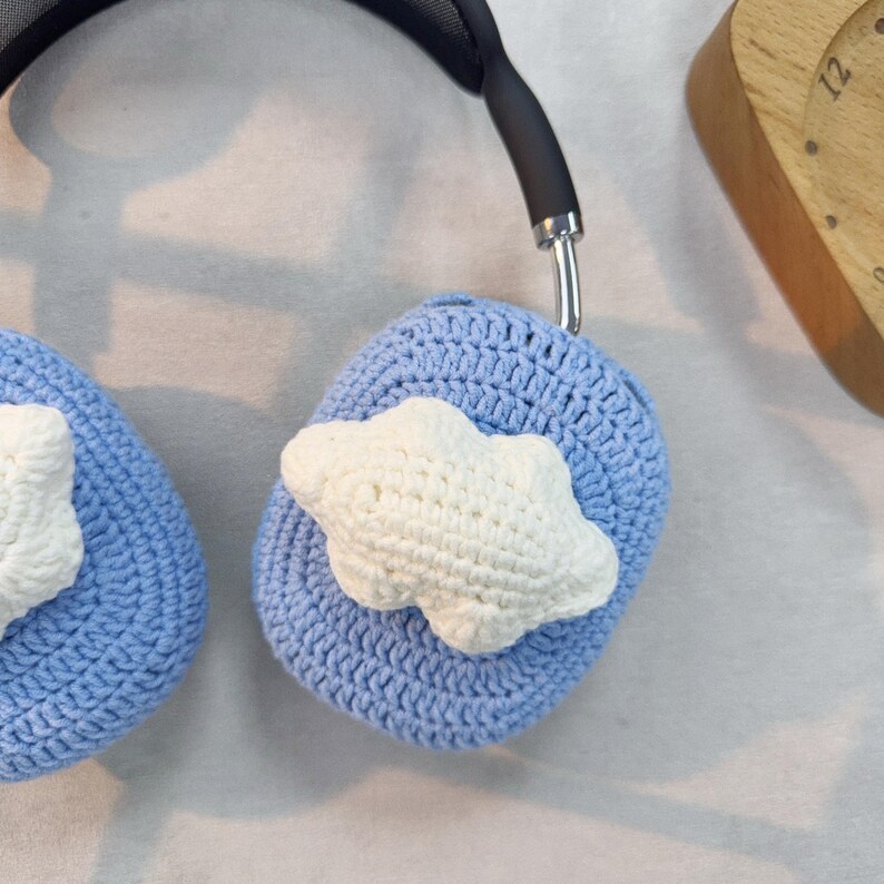 May include: A pair of blue crocheted headphone covers with white crocheted cloud accents.