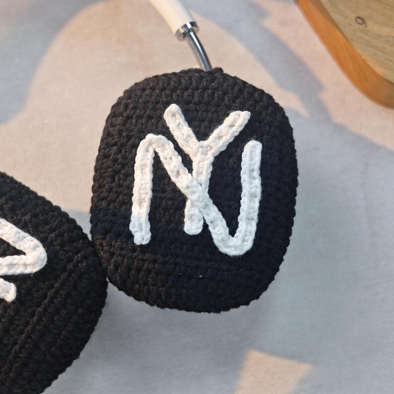 May include: Black crocheted headphone covers with a white "NY" logo.
