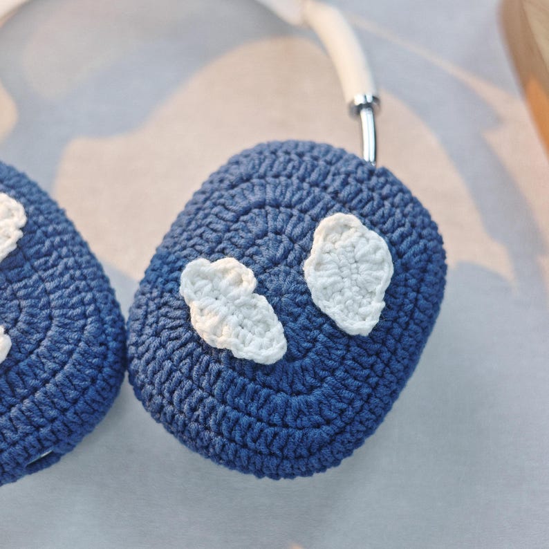 May include: A pair of blue crocheted headphone covers with white crocheted cloud designs.