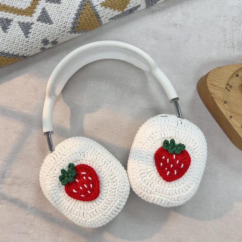 May include: White crocheted headphone covers with a red and green embroidered strawberry design.