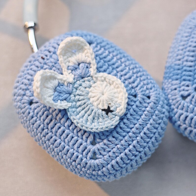 May include: A pair of blue crocheted ear warmers with a white and blue crocheted bunny applique on one ear warmer.
