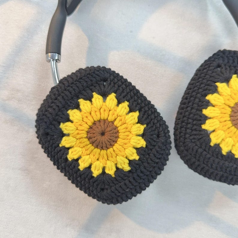 May include: Black crocheted headphone covers with a sunflower design in yellow and brown.