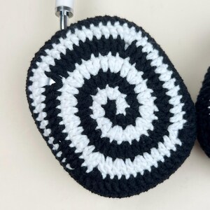 Pode incluir: Uma base de copo de croch&ecirc; em preto e branco com um design em espiral. A base de copo &eacute; redonda e tem uma al&ccedil;a para pendurar. O padr&atilde;o alternado em preto e branco cria um visual gr&aacute;fico arrojado. Feito &agrave; m&atilde;o.