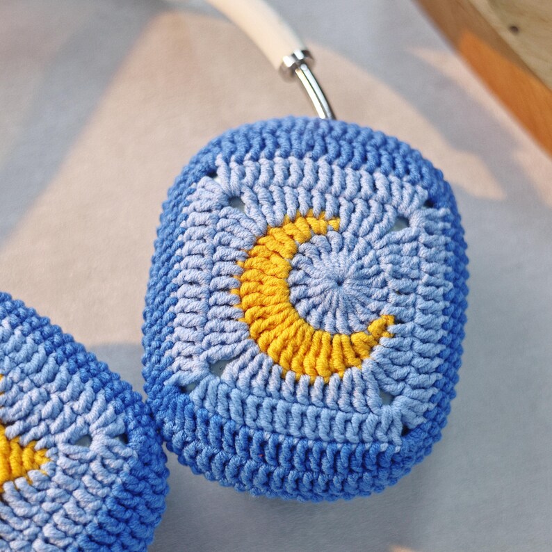 Puede incluir: Un par de fundas para auriculares de ganchillo azul con un dise&ntilde;o de media luna amarilla.
