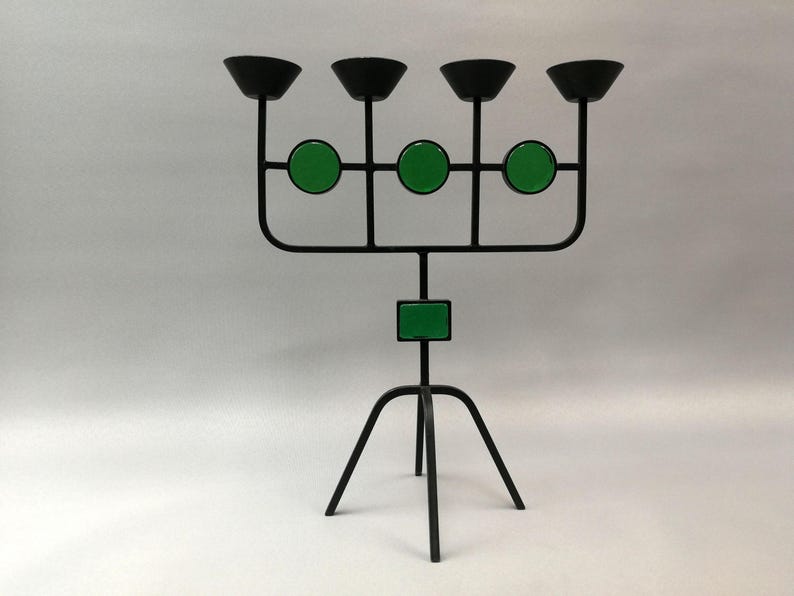 May include: A black metal candelabra with five candle holders and green accents. The candelabra has a tripod base.