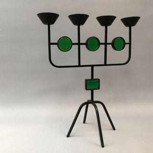 May include: Black metal candelabra with five candle holders and three green glass accents. The candelabra has a tripod base.