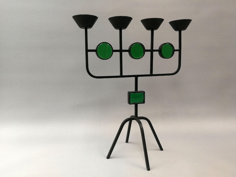 May include: Black metal candelabra with five candle holders and three green glass accents. The candelabra has a tripod base.