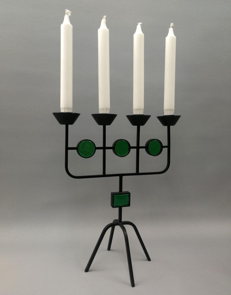 May include: A black metal candelabra with four candle holders and green glass accents. The candelabra has a tripod base.