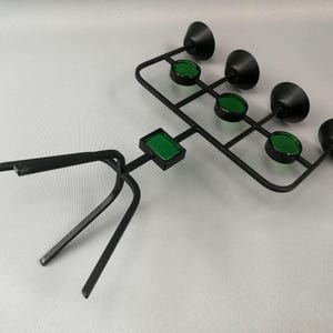 May include: A black metal candle holder with a tripod base and five green glass candle cups.
