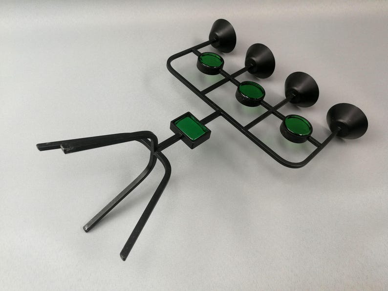 May include: A black metal candle holder with a tripod base and five green glass candle cups.