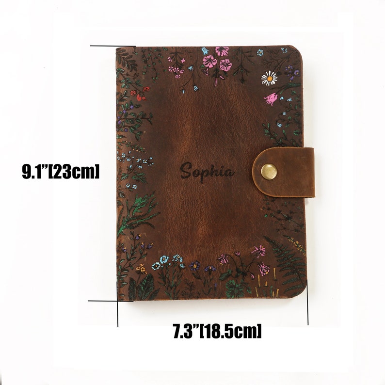 May include: A brown leather journal featuring a floral print border and the name Sophia engraved in the center. The journal includes a brass snap closure and measures 9.1 inches by 7.3 inches as indicated by the text on the image.