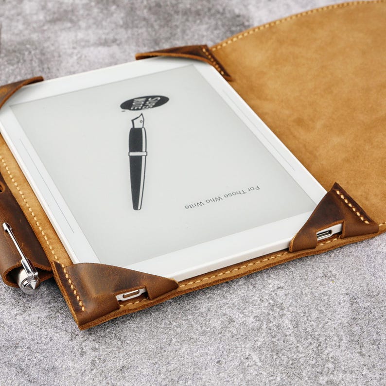 May include: A brown leather case for an e-reader with a pen and the text "For those who write" on the inside of the case.