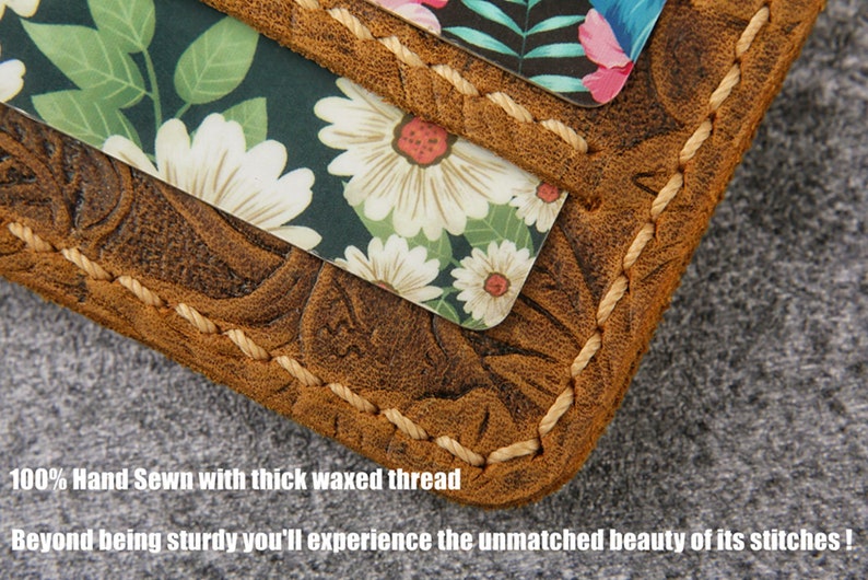 May include: Close-up of a brown leather wallet with a floral pattern embossed on the surface. The wallet is stitched with a thick, waxed thread. The text "100% Hand Sewn with thick waxed thread" and "Beyond being sturdy you'll experience the unmatched beauty of its stitches!" is visible below the wallet.