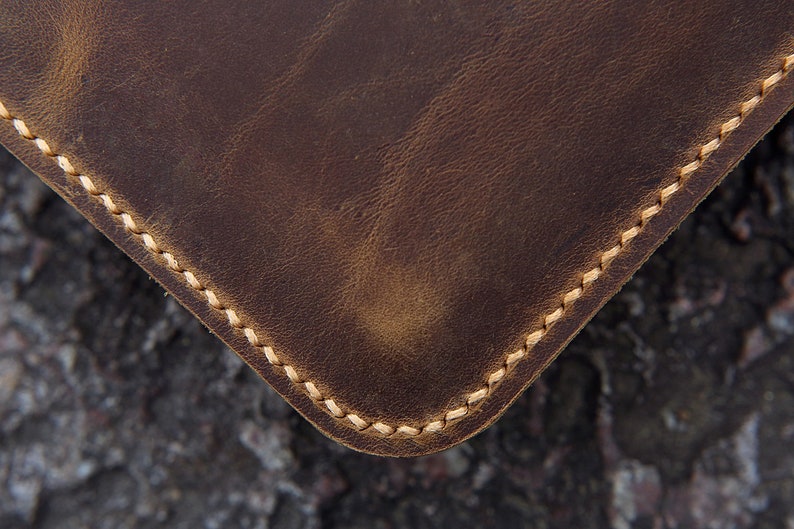 May include: Close-up of a brown leather item with a stitched edge. The stitching is a light brown color.