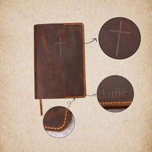 May include: A brown leather book with a cross embossed on the cover. The name "James" is also embossed on the cover. The book has a stitched border and a ribbon bookmark.