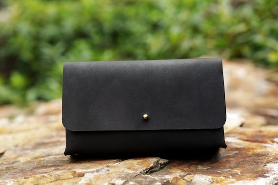 Hand-stitched black leather pouch built specifically to wrangle a MacBook charger and its cable — looks like a small luxury accessory, not a tangled mess on your desk.