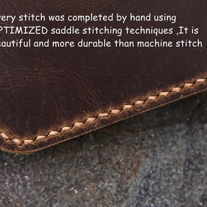 Op de afbeelding: Een donkerbruin lederen item met lichtgekleurde, met de hand genaaide zadelsteken langs de afgeronde rand. De tekst op het oppervlak luidt: Every stitch was completed by hand using OPTIMIZED saddle stitching techniques ,It is beautiful and more durable than machine stitch