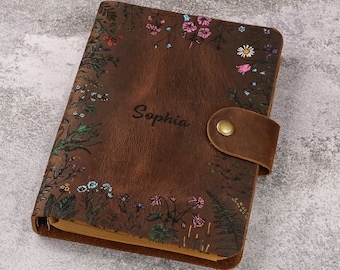 May include: A brown leather journal with a floral design and the name "Sophia" embossed on the front. The journal has a flap closure with a button.