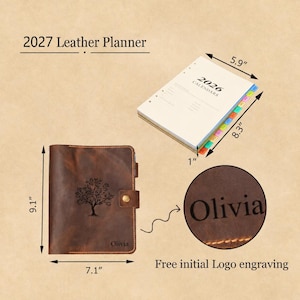 May include: A brown leather planner with a tree engraving and the name Olivia, measuring 9.1 inches by 7.1 inches. It includes a 2026 calendar insert measuring 8.3 inches by 5.9 inches by 1 inch, featuring colorful tabbed dividers and text.