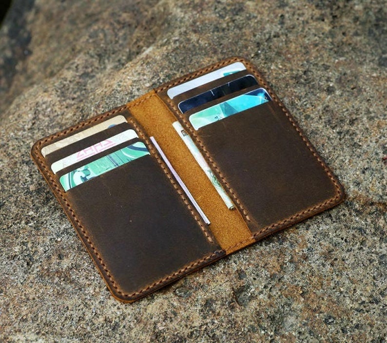 May include: A brown leather wallet with multiple card slots and a cash pocket. The wallet is open and has several cards inside.