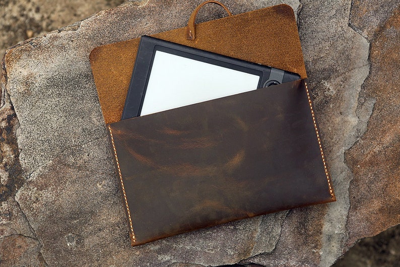 May include: A brown leather case with a flap that folds over to protect a tablet or e-reader. The case has a distressed look and is stitched with a light brown thread.