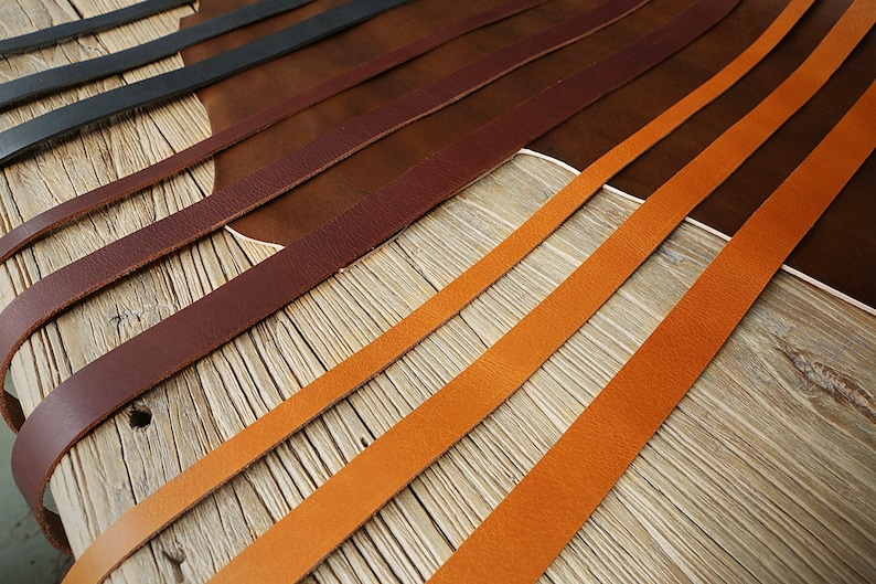 May include: Close-up of leather strips in various shades of brown and orange, arranged in parallel lines on a wooden surface.
