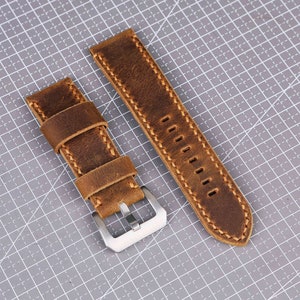 May include: Two brown leather watch straps with stitching. One strap has a buckle.