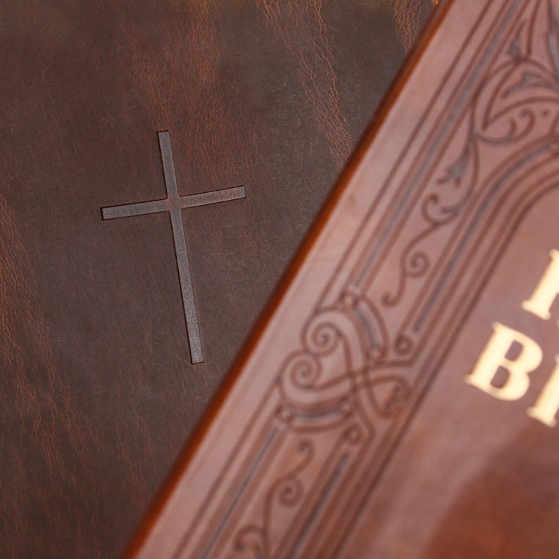 May include: Close-up of two brown leather-bound books. One features a debossed cross, the other has ornate gold lettering and decorative patterns. The books have a vintage, classic aesthetic.