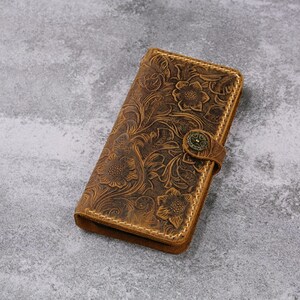 May include: A brown leather wallet with a floral embossed design and a brass button closure.