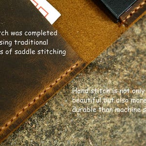 May include: Close-up of a brown leather surface with a stitched edge. The text "Every stitch was completed by hand using traditional techniques of saddle stitching" is visible. The text "Hand stitch is not only beautiful, but also more durable than machine stitch" is also visible.