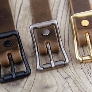May include: Three leather belts with different colored buckles. The buckles are black, silver, and gold.