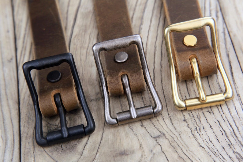 May include: Three leather belts with different colored buckles. The buckles are black, silver, and gold.