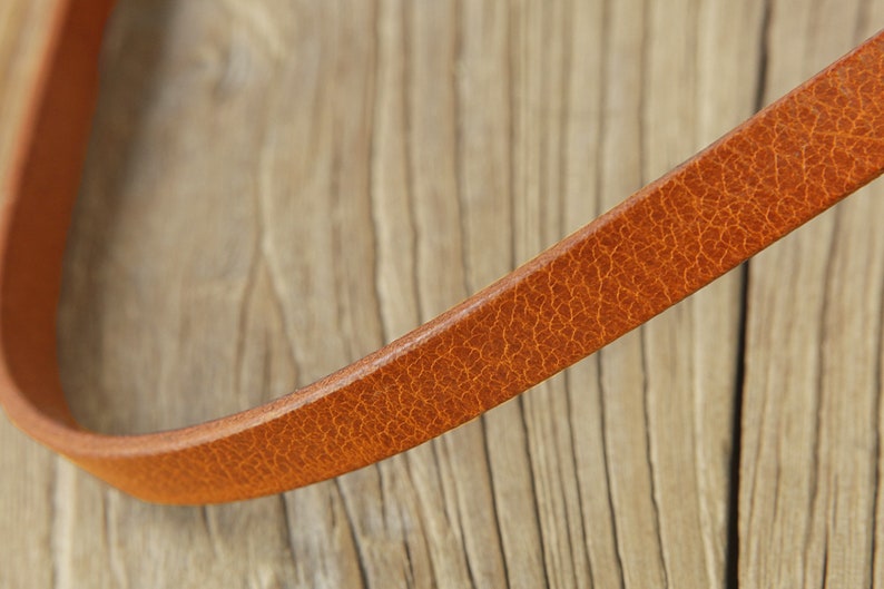 May include: Close-up of a brown leather strap with a textured surface.