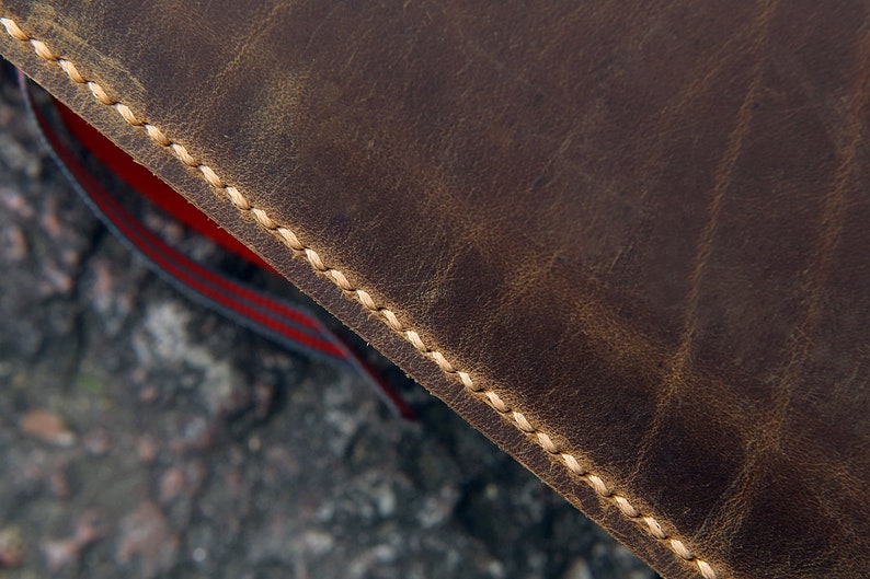 May include: Close-up of brown leather with a stitched edge. The stitching is a light beige color.