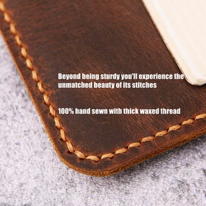 May include: Close-up of a brown leather item with visible stitching. The text reads "Beyond being sturdy you'll experience the unmatched beauty of its stitches" and "100% hand sewn with thick waxed thread."