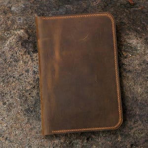 May include: A brown leather notebook with stitched edges.